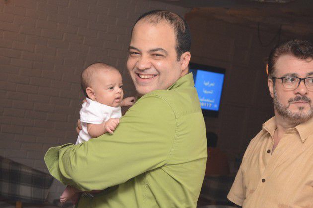 شريف باهر يحمل طفلاً رضيعاً